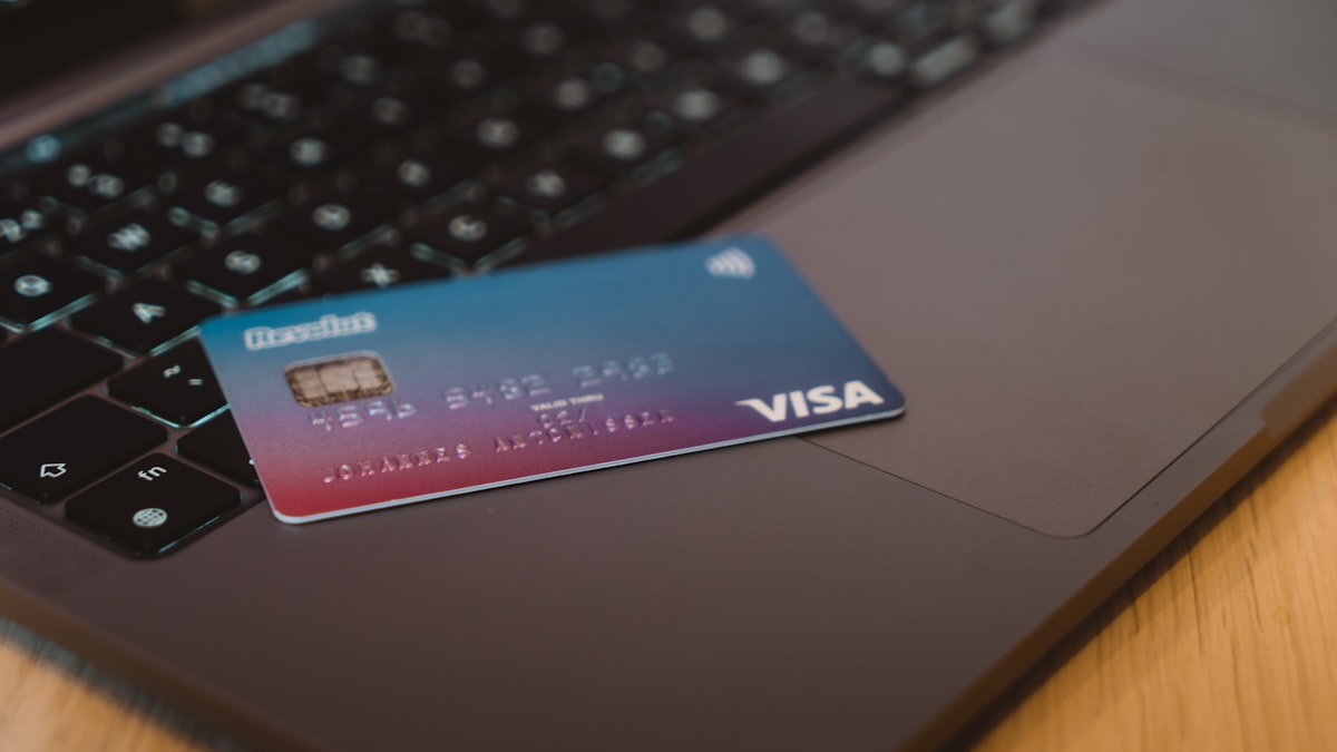 Credit card next to a laptop showing an online checkout page